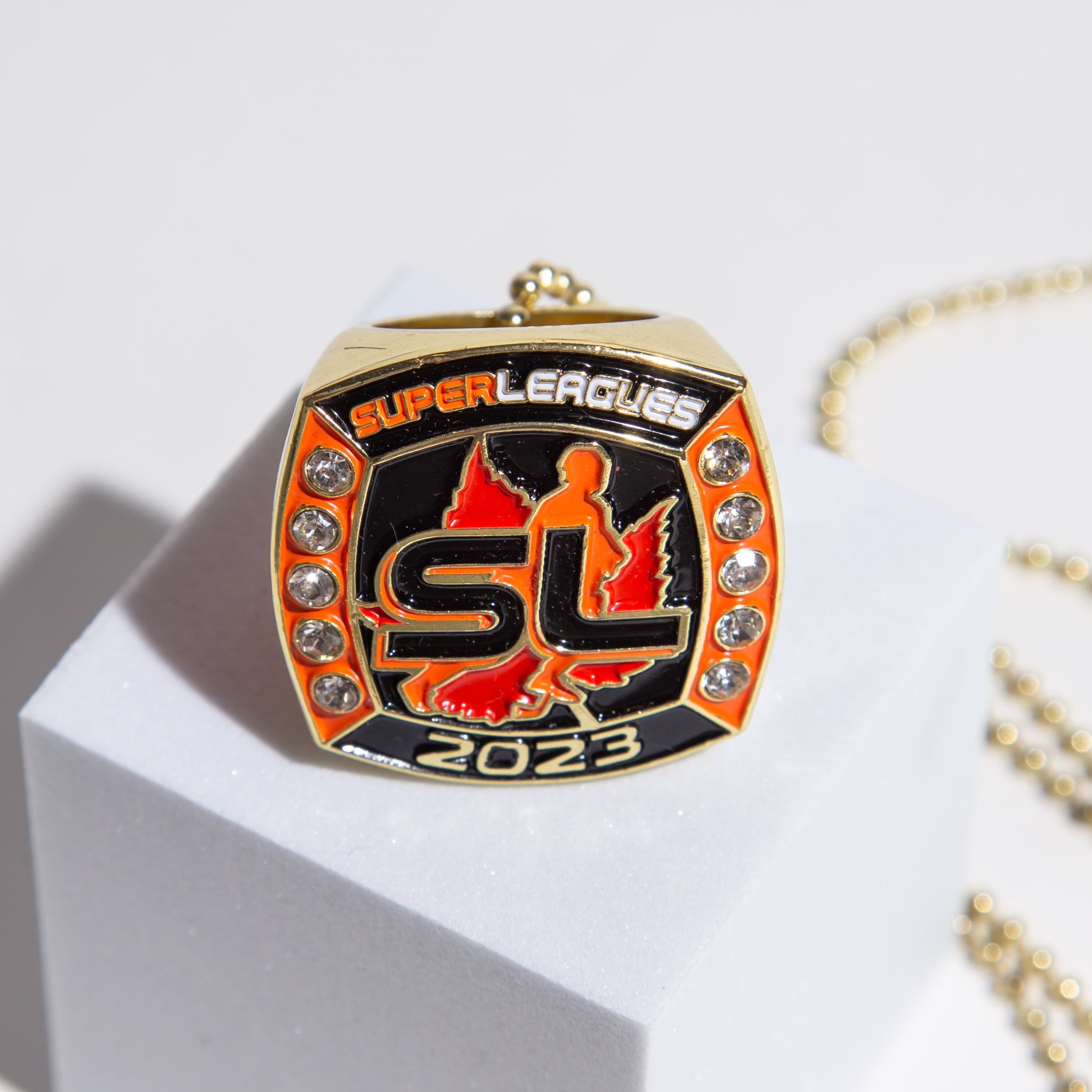 Custom Super Leagues 2023 championship ring featuring gold accents and vibrant orange highlights, designed for elite league winners.