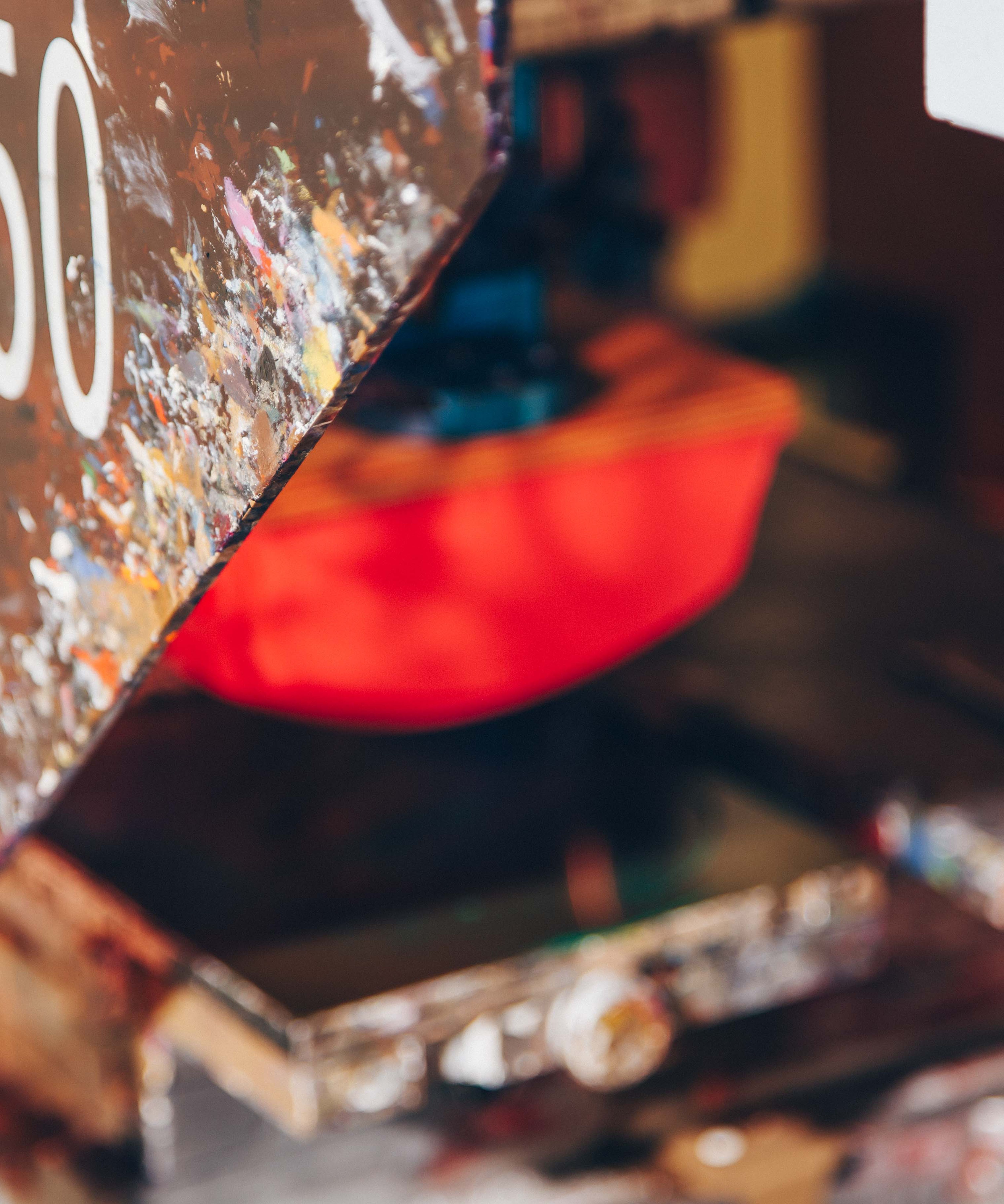 A close-up of a paint-splattered pad printing machine, used for precision printing on products. The machine's vibrant colors and well-used appearance highlight its role in creating detailed custom prints on various surfaces.