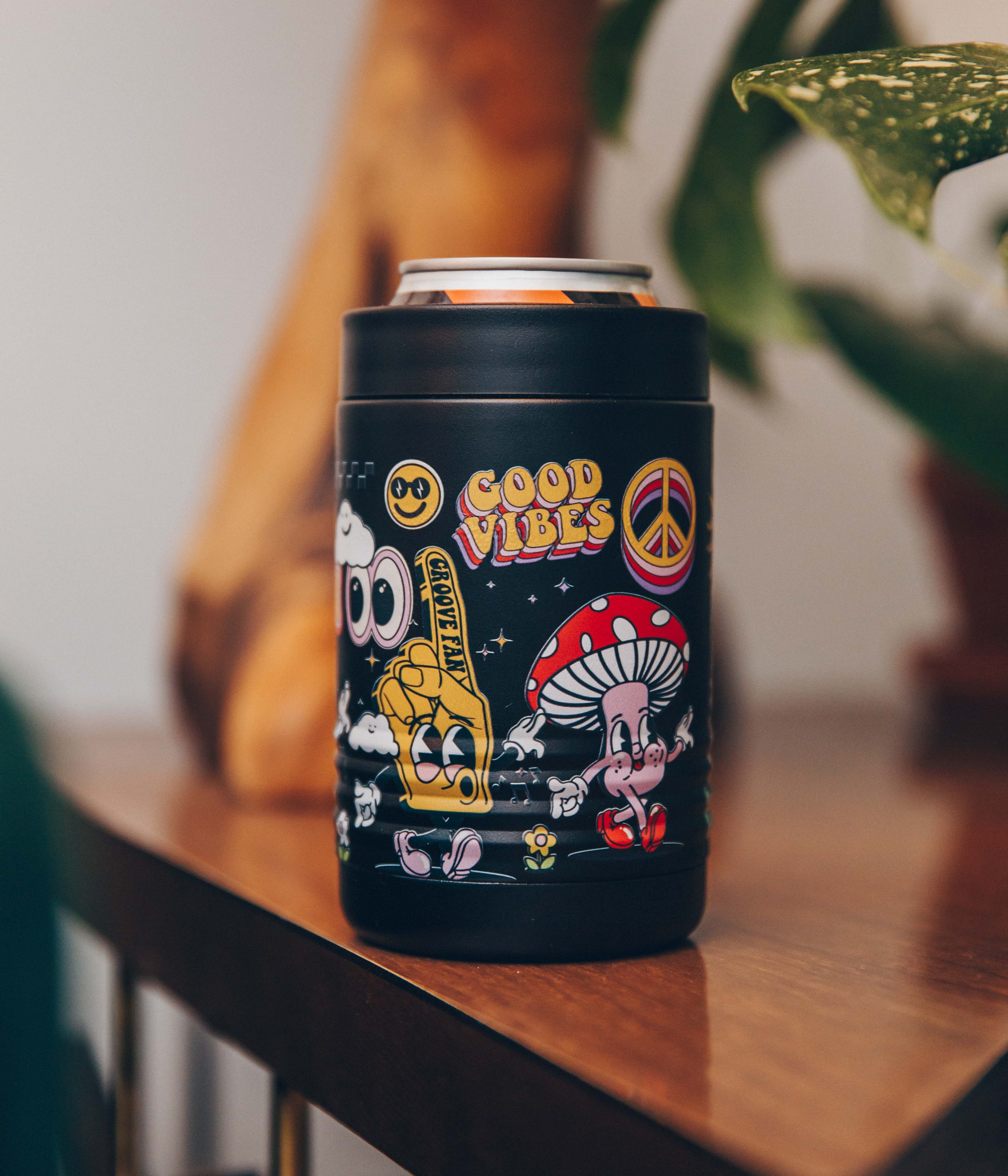 Black can holder with colorful retro designs and 'Good Vibes' text on a wooden table.