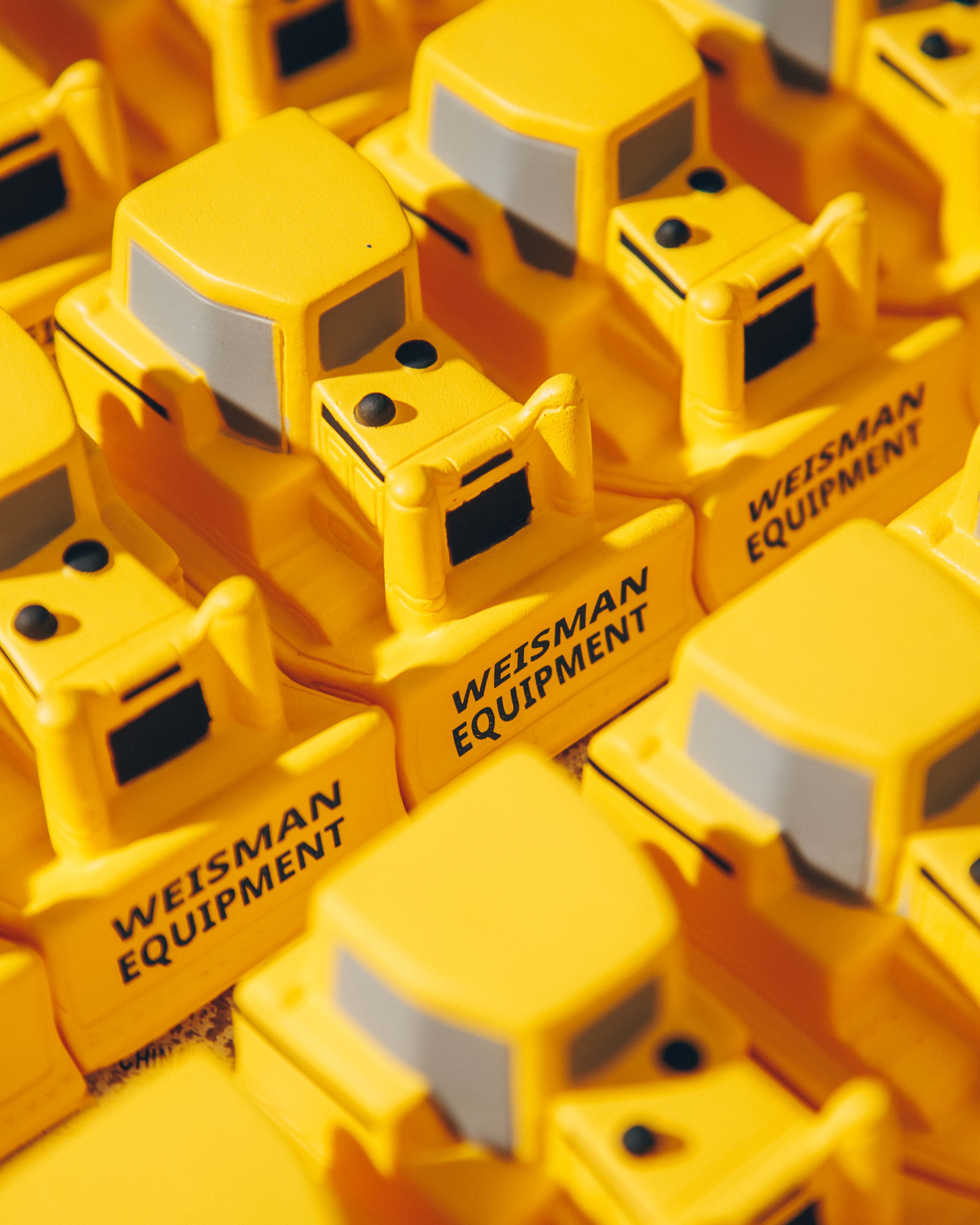 Close-up of yellow toy bulldozers with 'Weisman Equipment' printed on them.