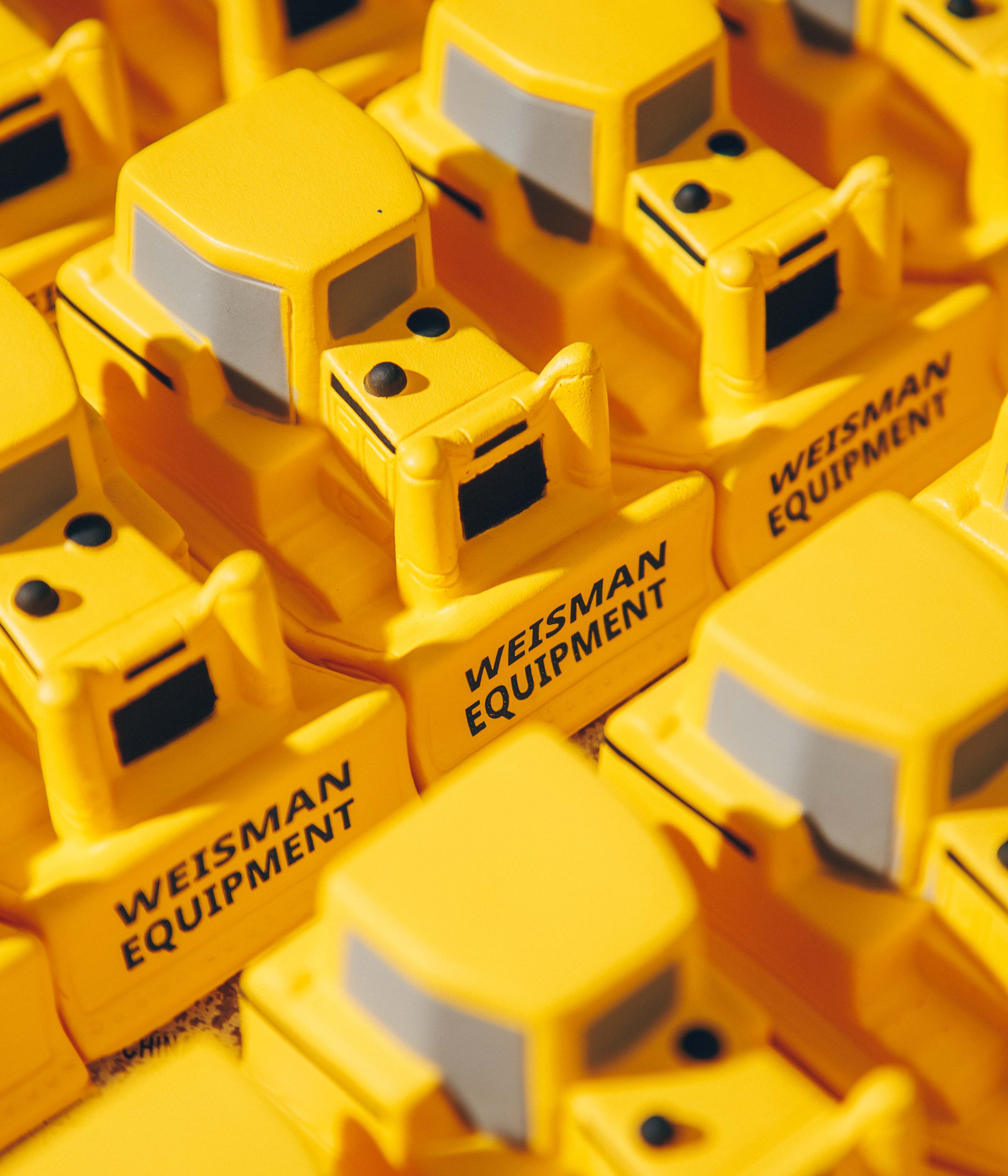 Close-up of yellow toy bulldozers with 'Weisman Equipment' printed on them.