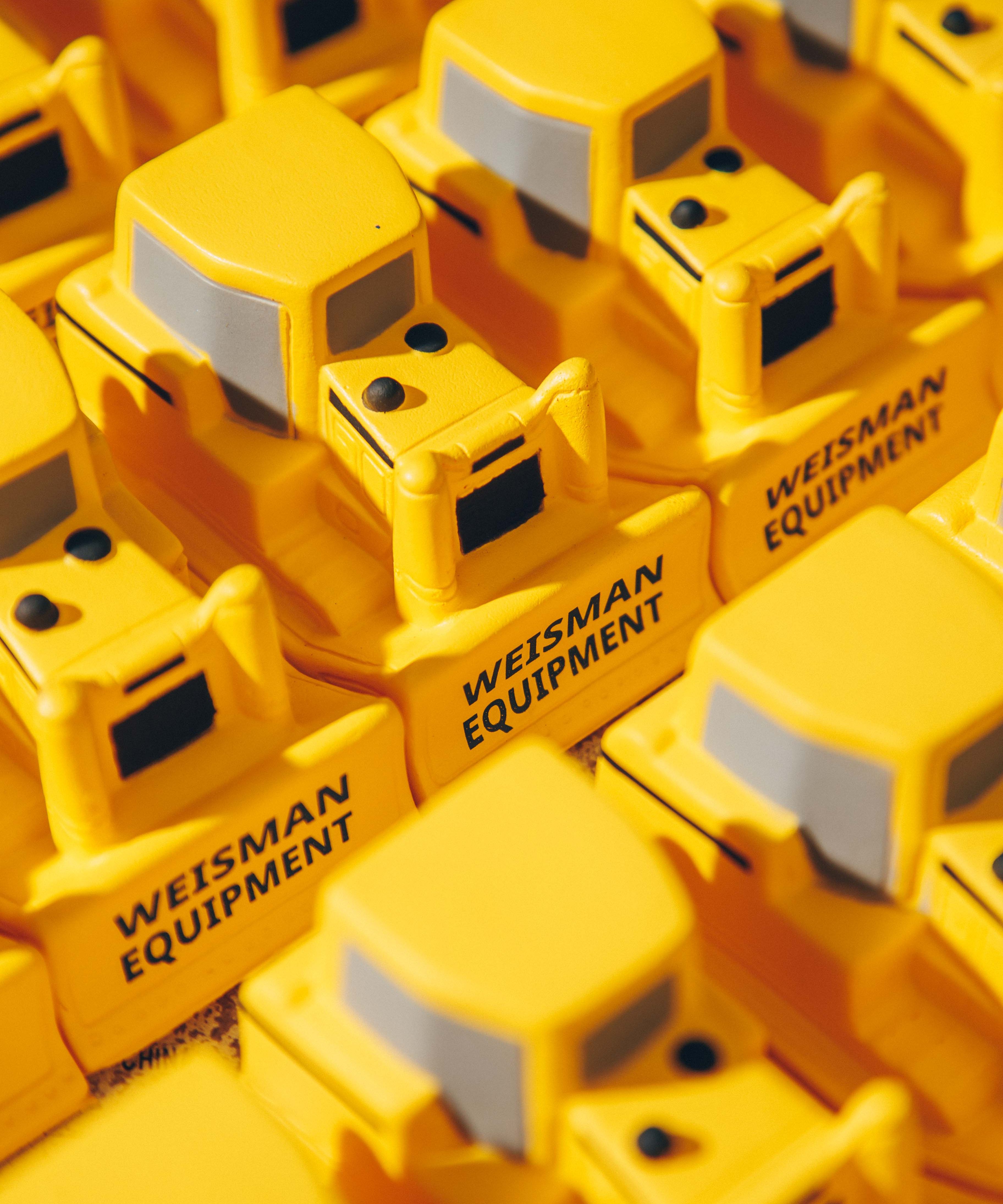 Close-up of yellow toy bulldozers with 'Weisman Equipment' printed on them.