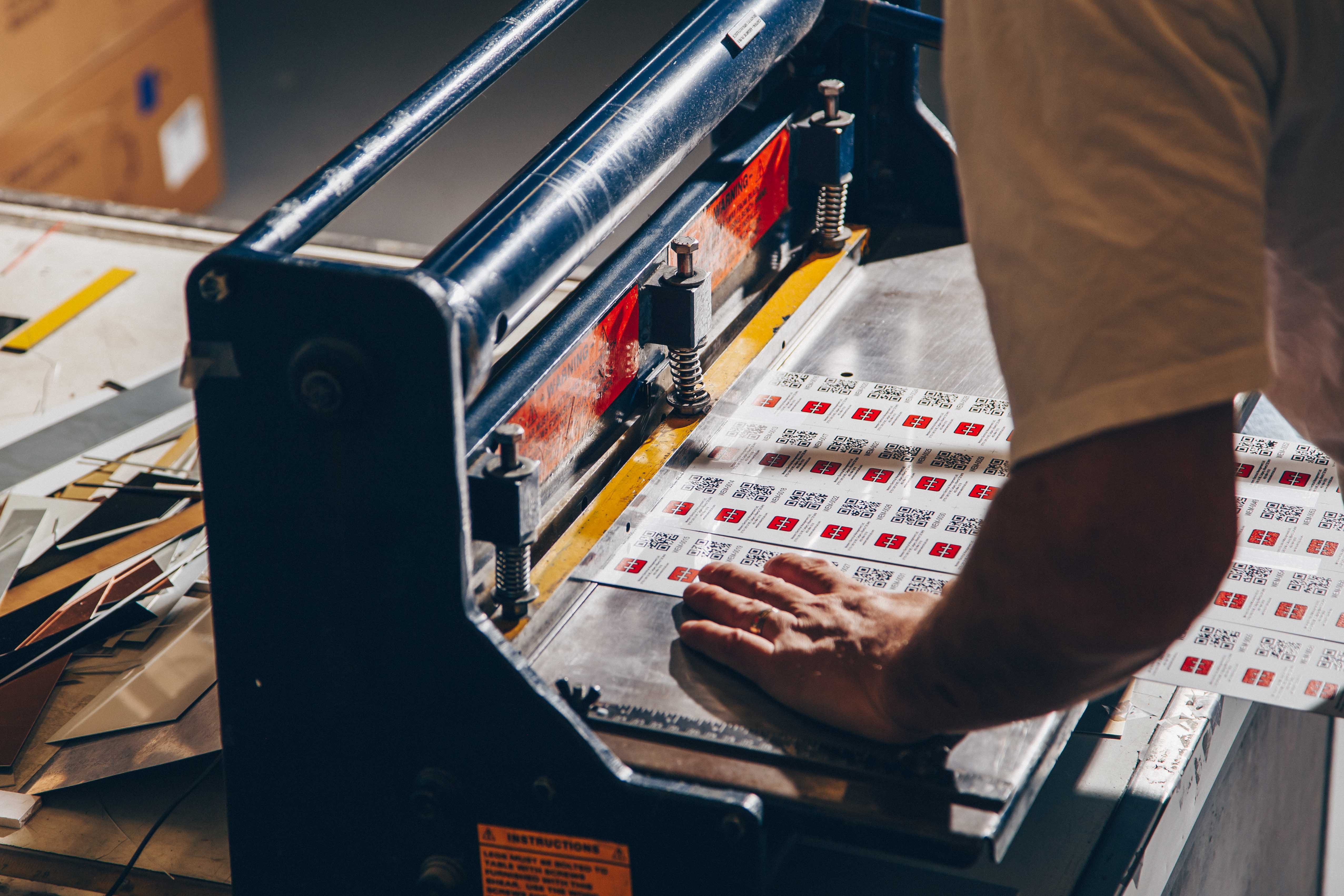 Person using cutting device to split sheet of metal labels apart.