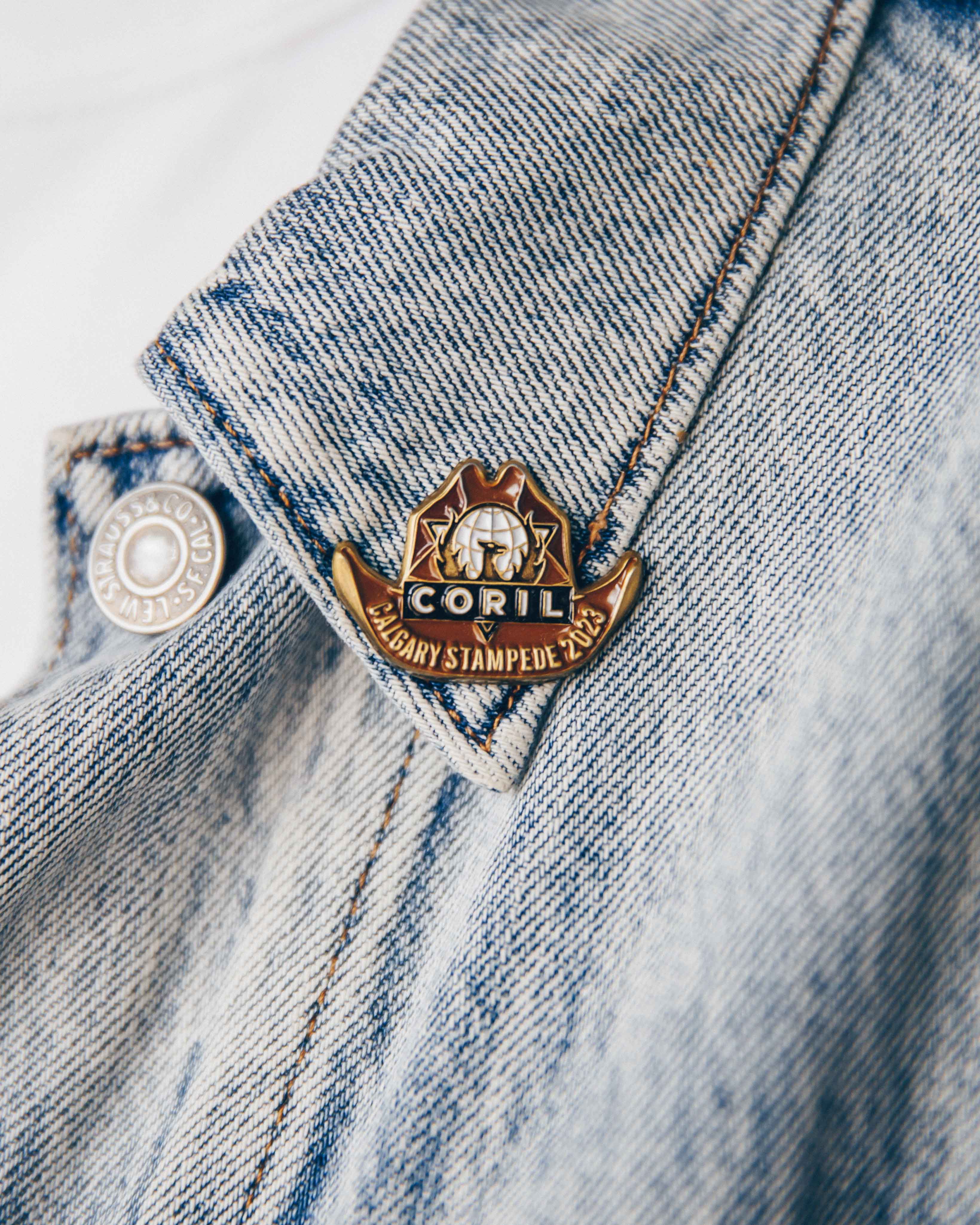 Close-up of a Calgary Stampede 2023 pin on a denim jacket collar.
