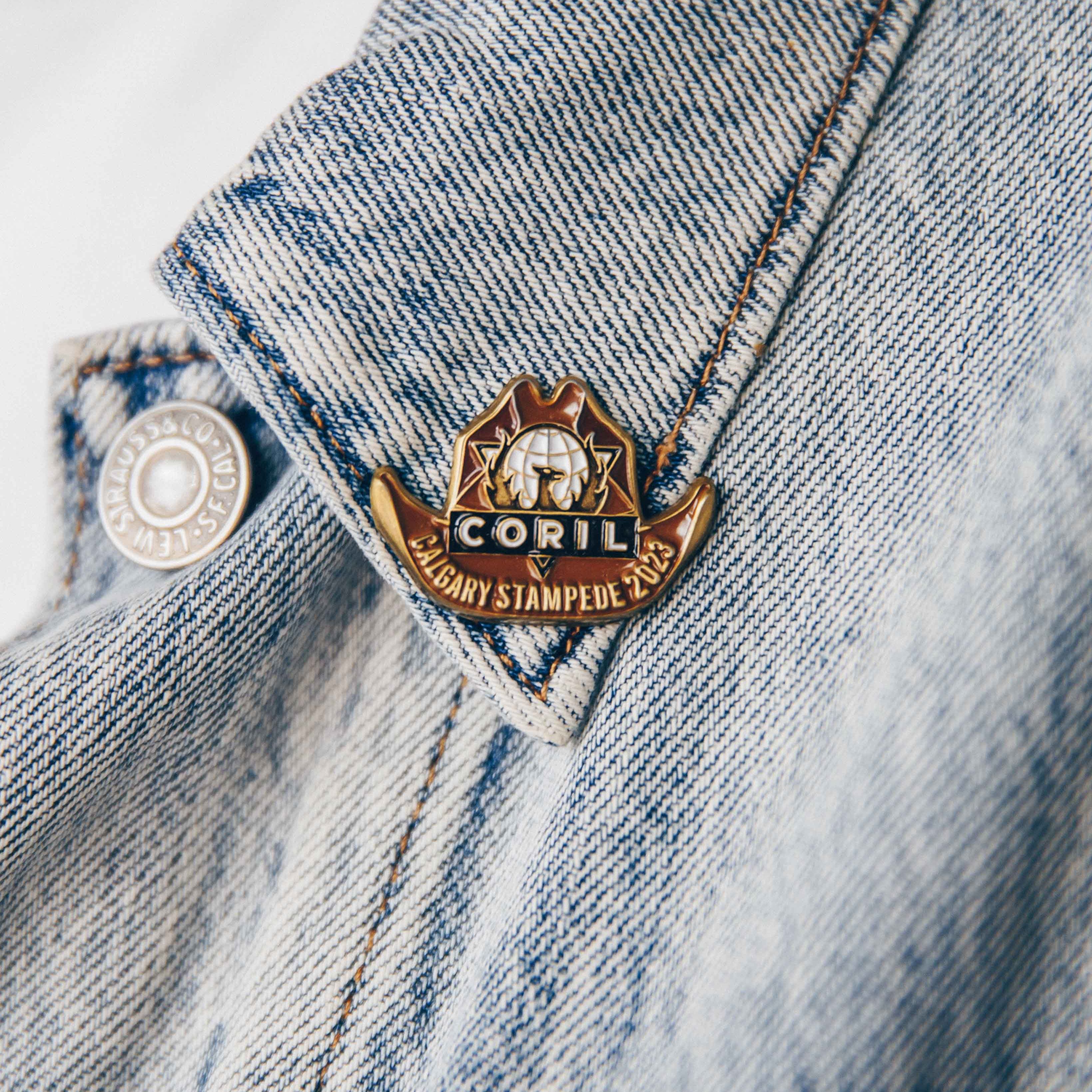 Close-up of a Calgary Stampede 2023 pin on a denim jacket collar.