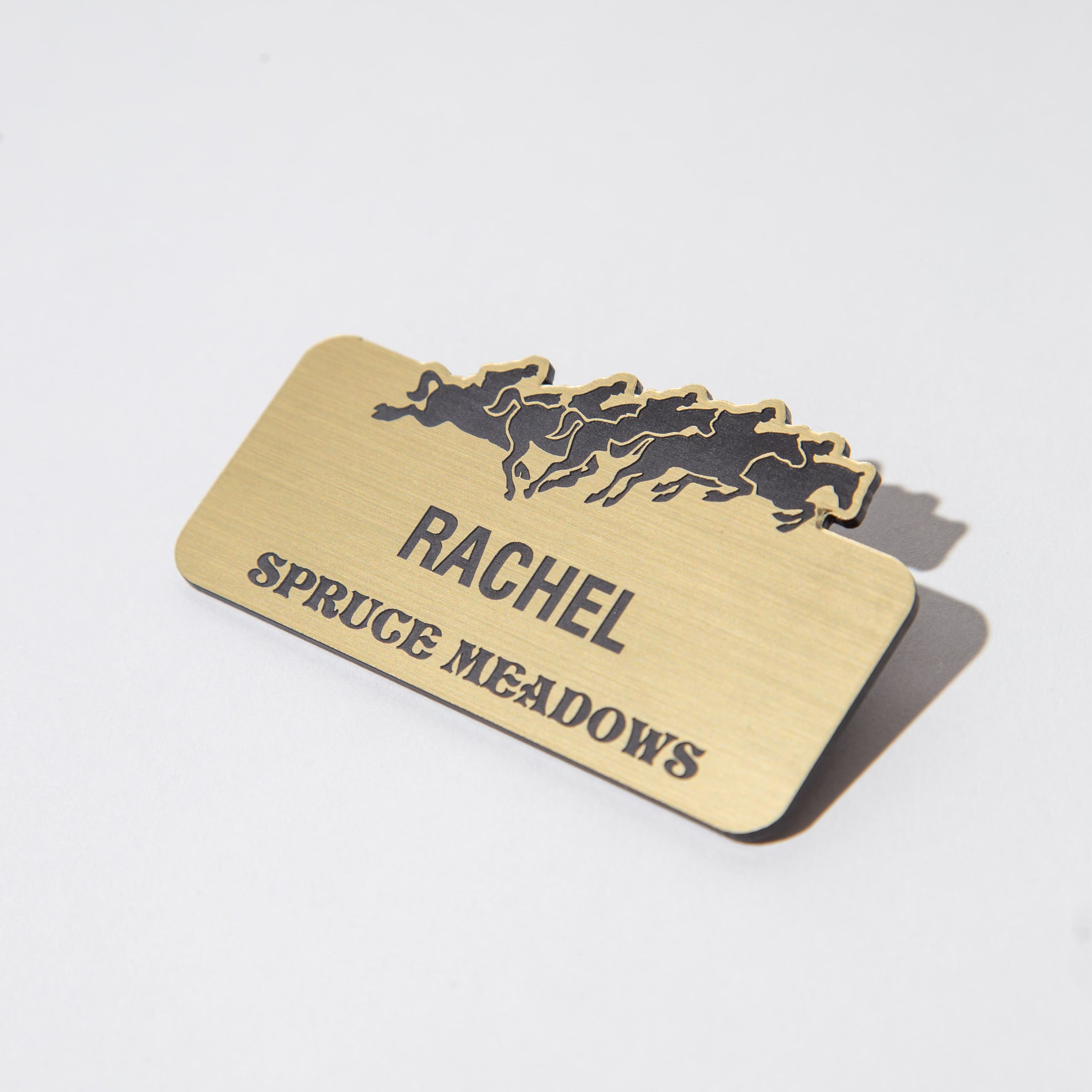 Brass name tag with horse silhouettes and the name 'Rachel' above 'Spruce Meadows'.