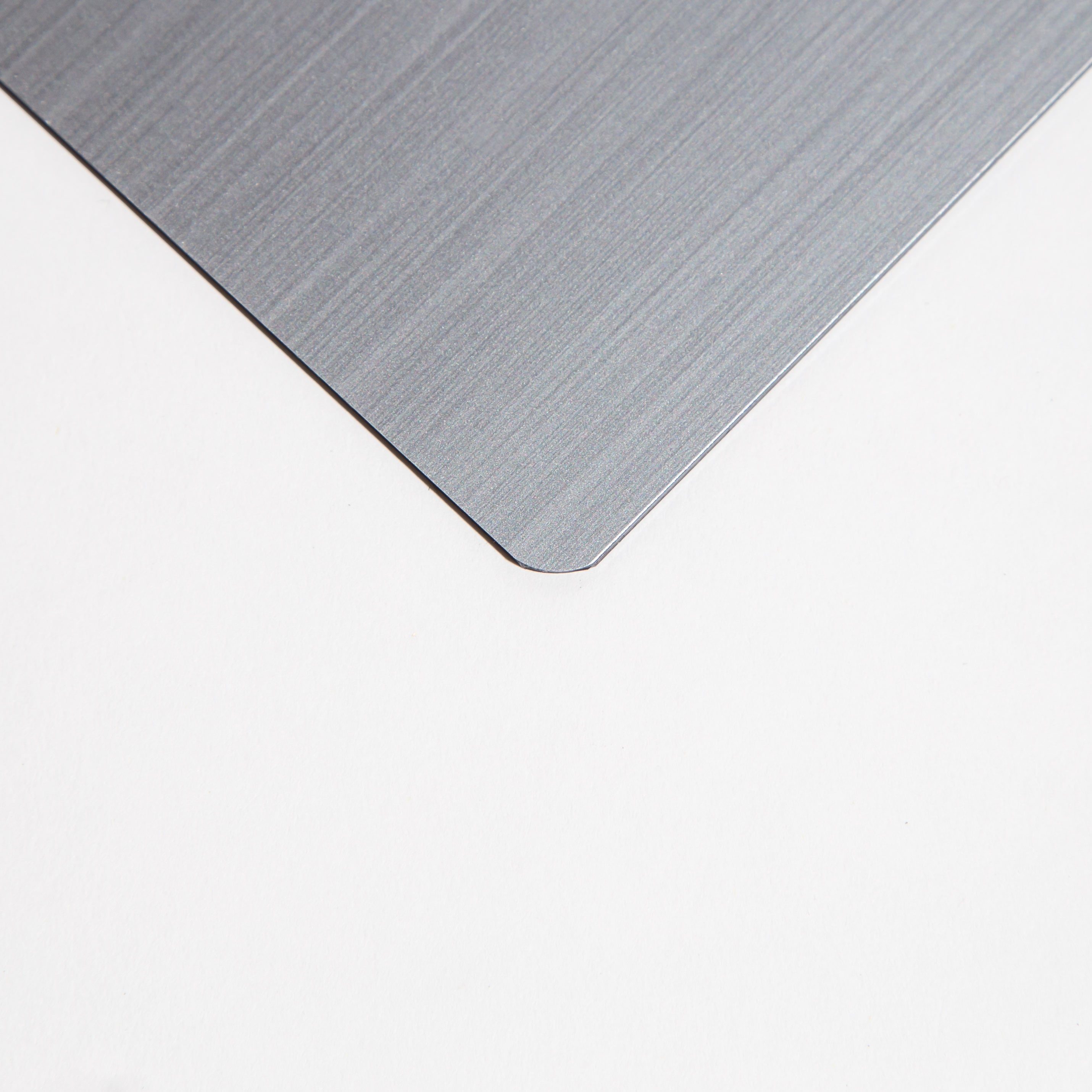 Close-up of a brushed metal sheet corner on a white background.