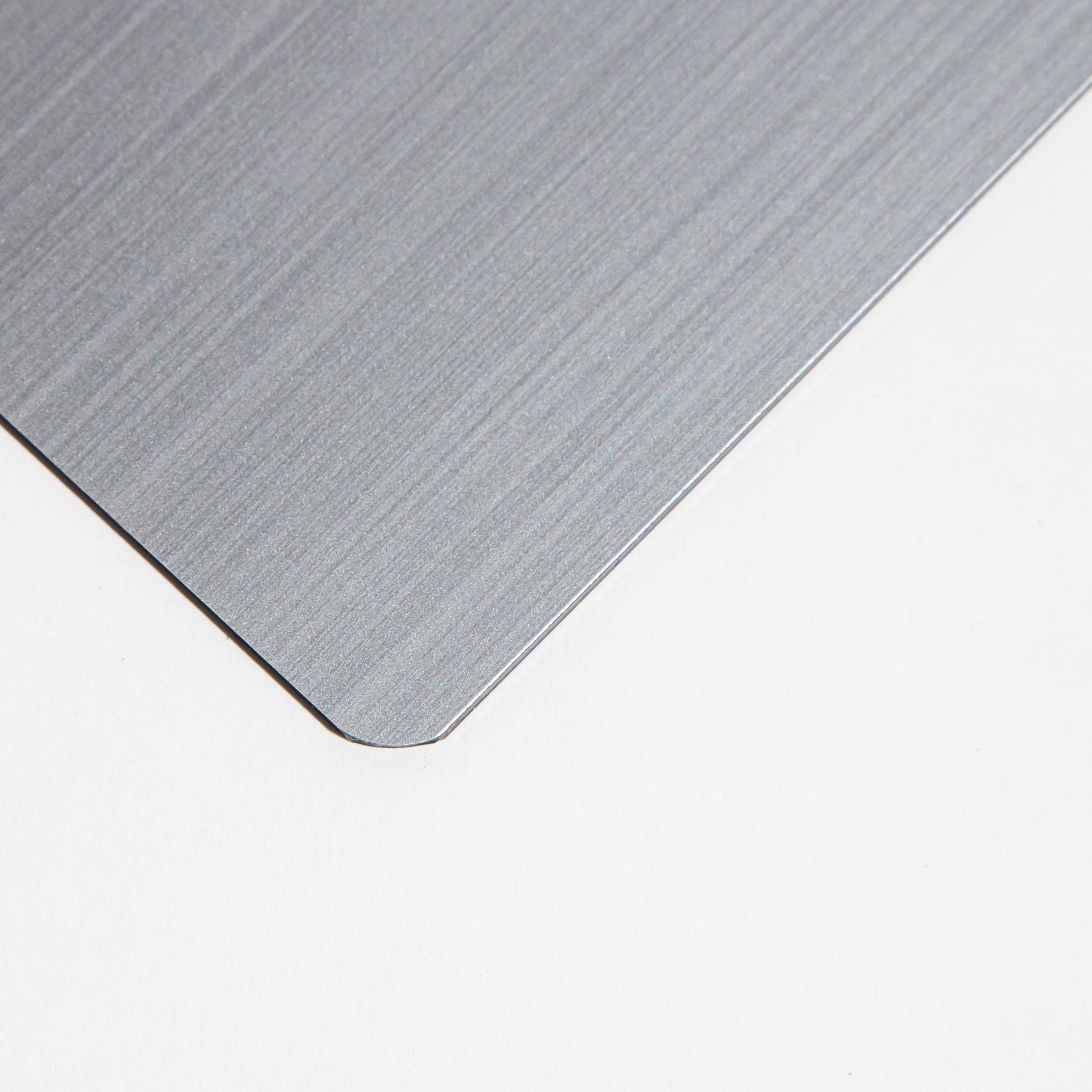 Close-up of a brushed metal sheet corner on a white background.