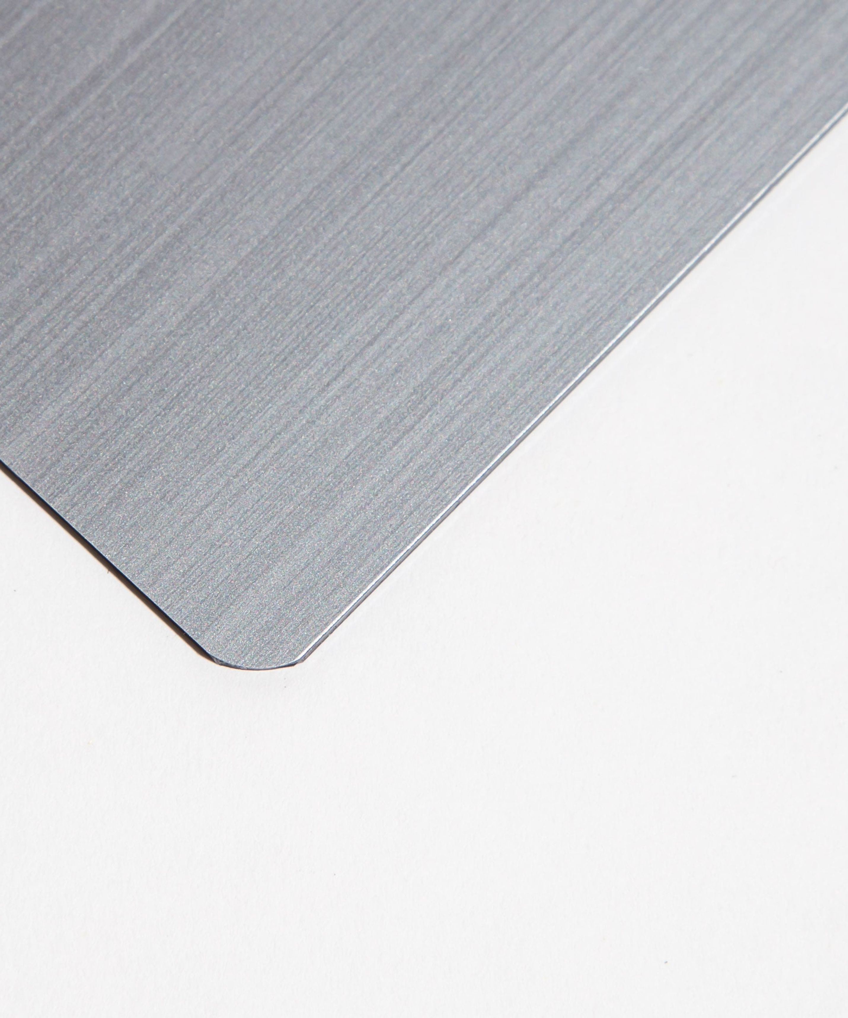 Close-up of a brushed metal sheet corner on a white background.