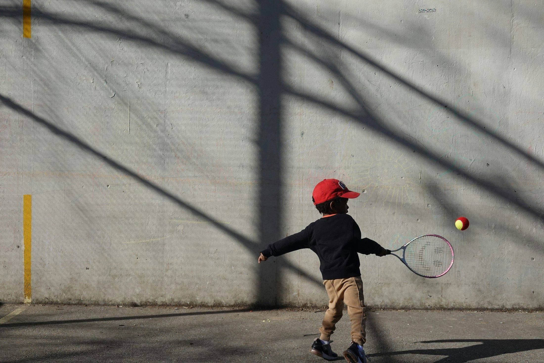 Enfant frappant une balle contre un mur d’entraînement