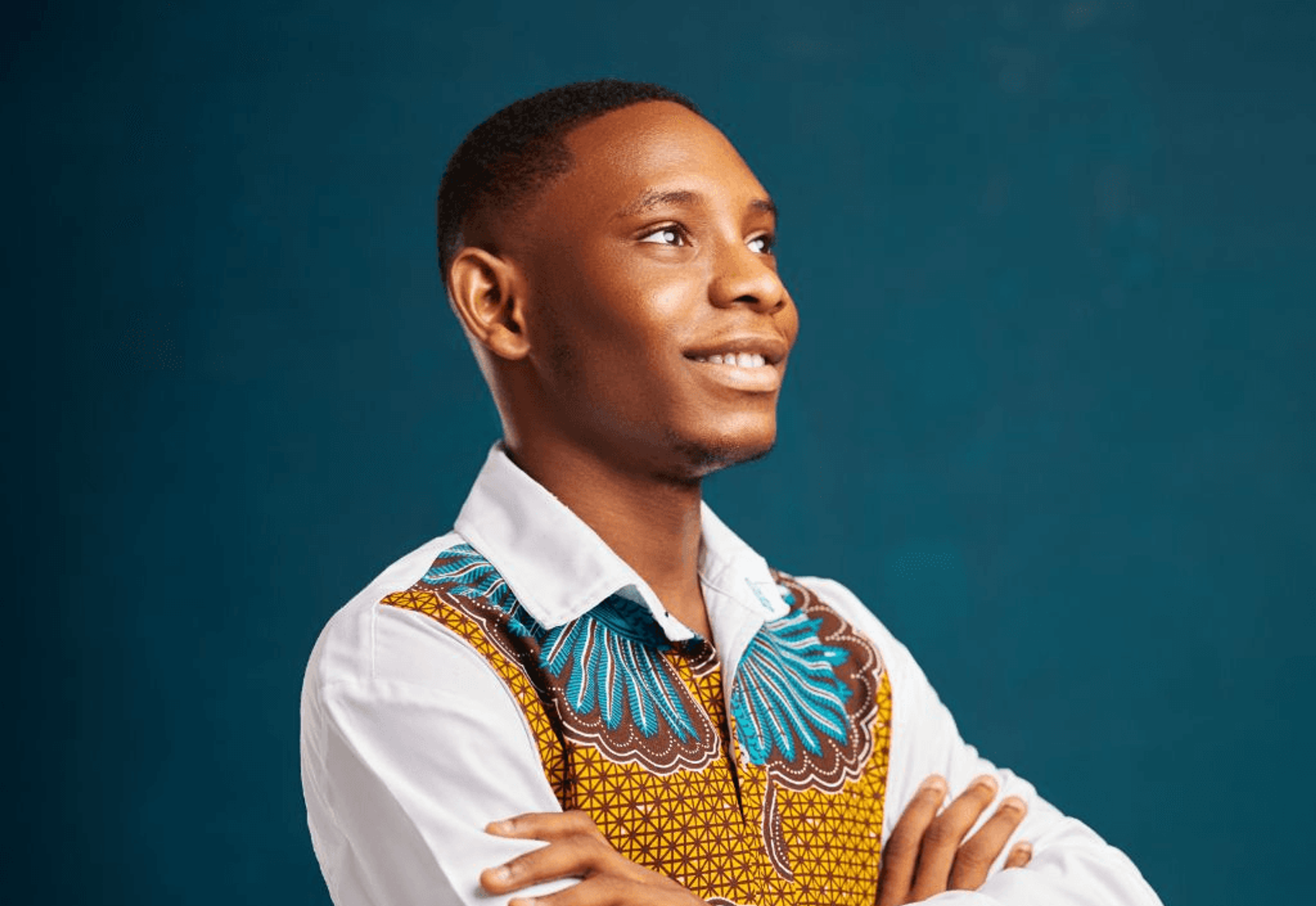 Bright Kumedzro in a white shirt with a kente-pattern vest, against a teal background