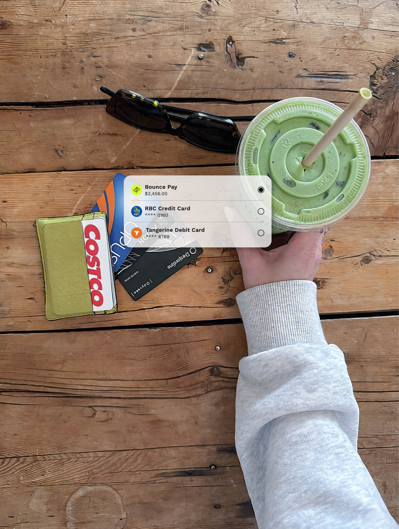 Hand holding an iced matcha drink on a wooden table
