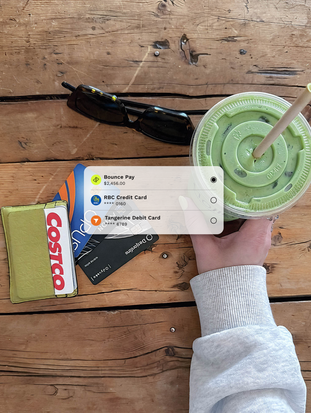 Hand holding an iced matcha drink on a wooden table