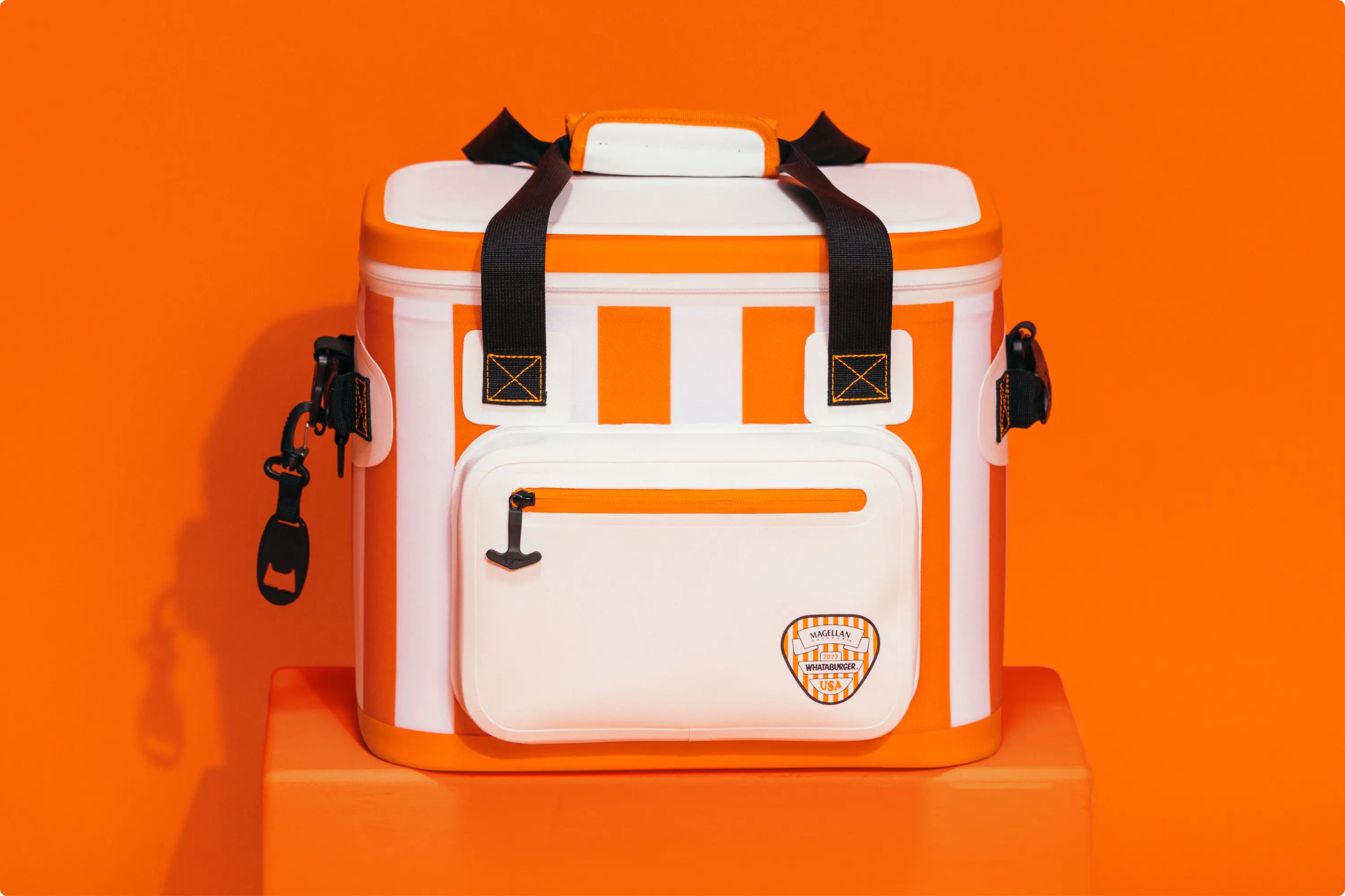 A Whataburger and Magellan Outdoors cooler on a bright orange background