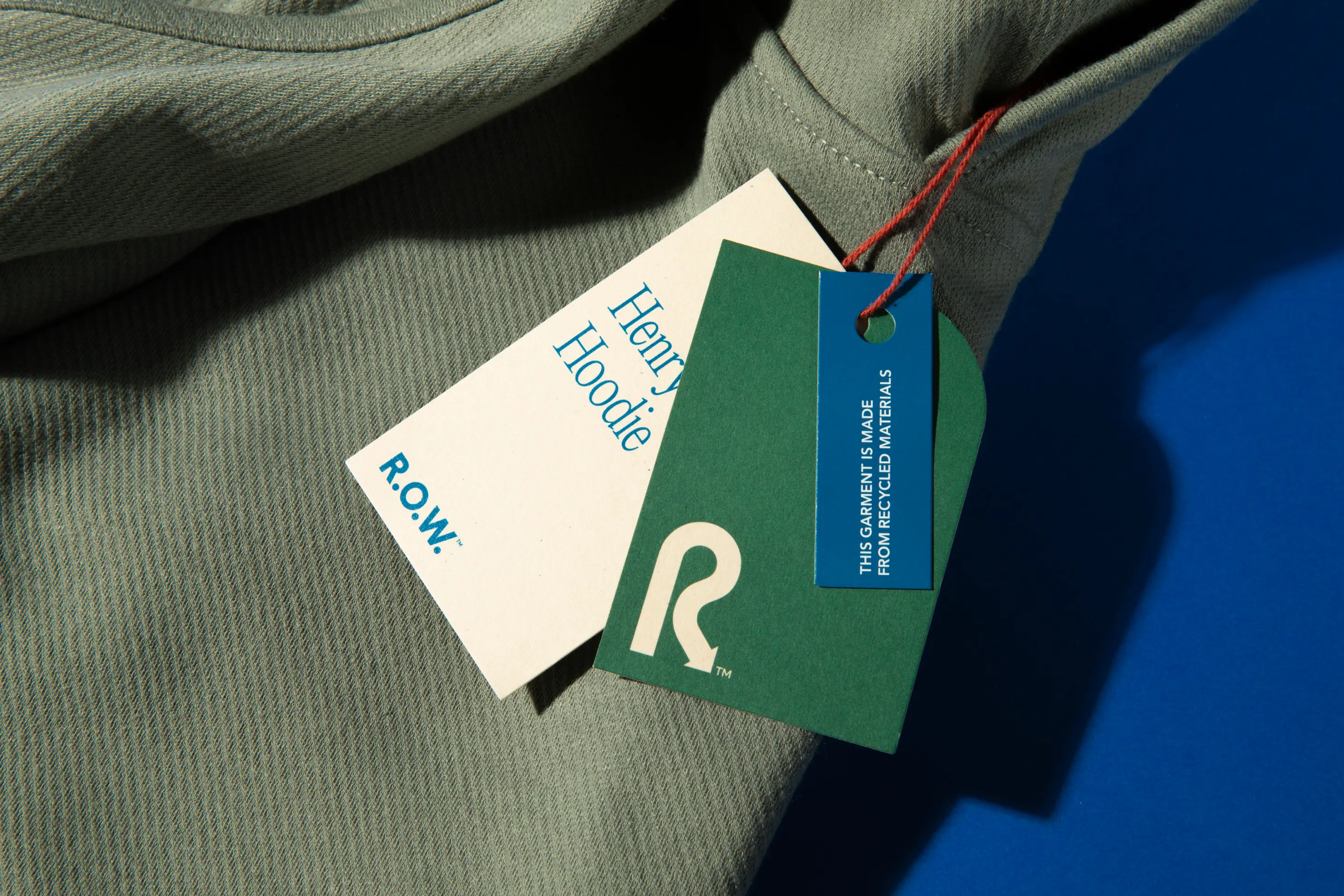 R.O.W Henry Hoodie and retail tags on a blue background