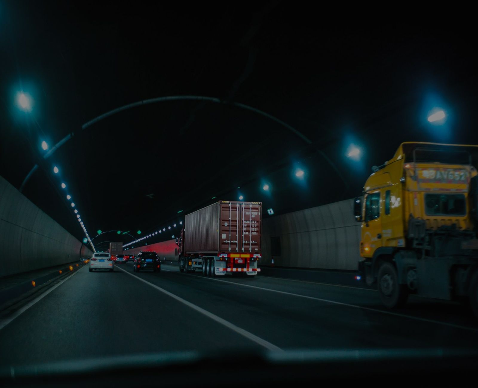 Vrachtwagens en auto's rijden 's nachts door een verlichte tunnel.