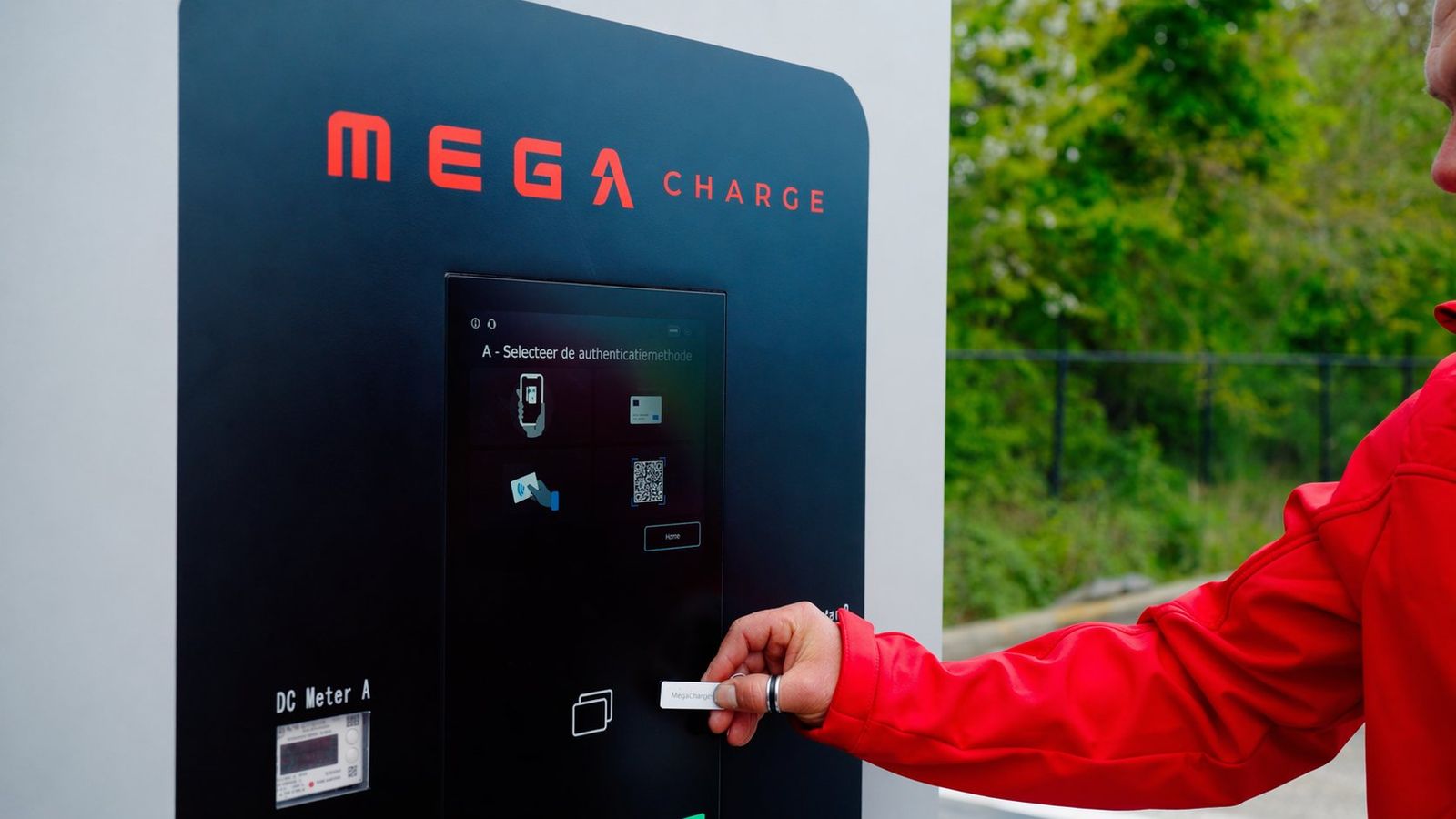 Een hand houdt een laadpas tegen het scherm van een MEGA Charge-laadpaal om te starten met laden.