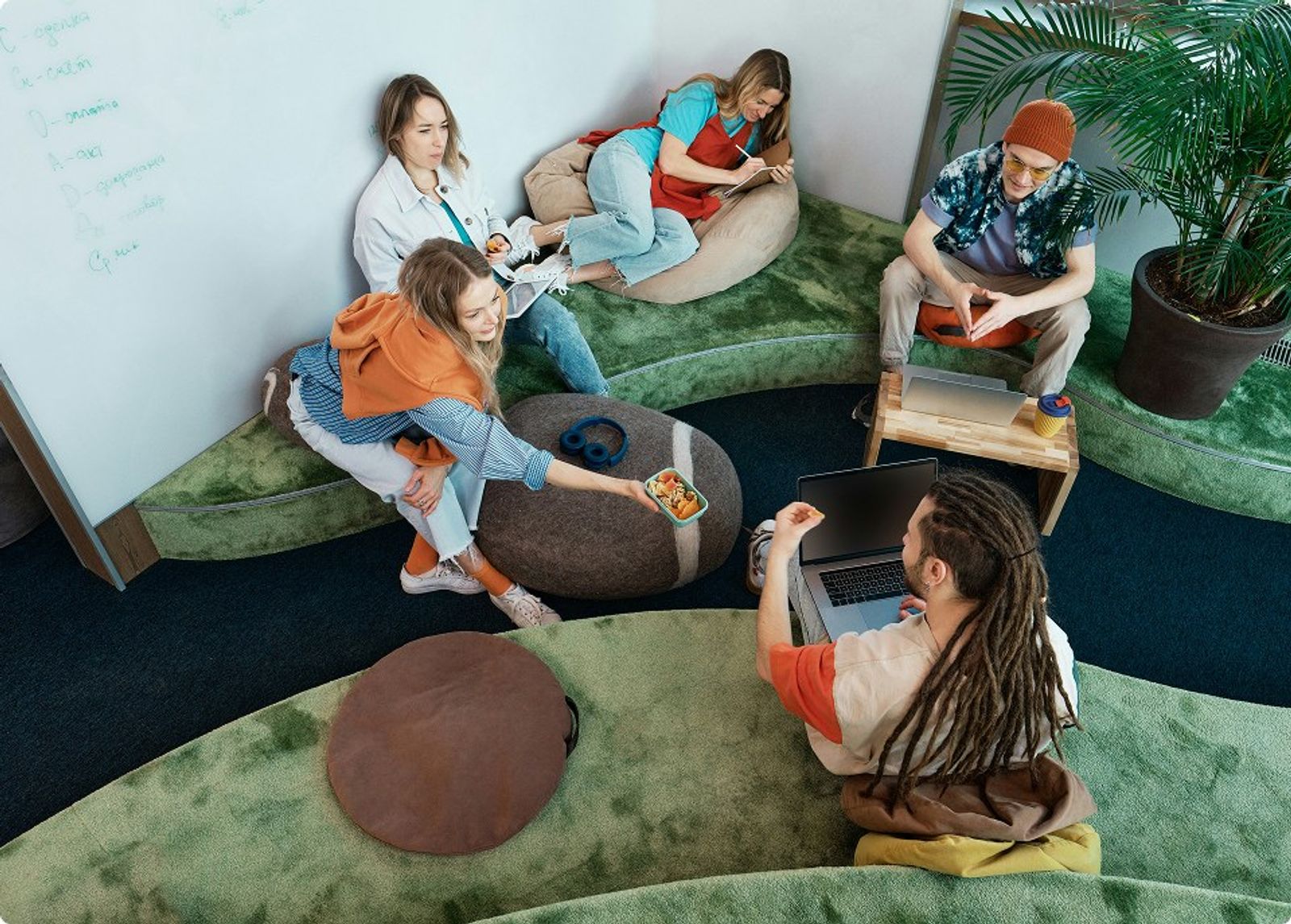 Een team werkt op zitzakken en laptops voor een whiteboard tijdens een workshop.