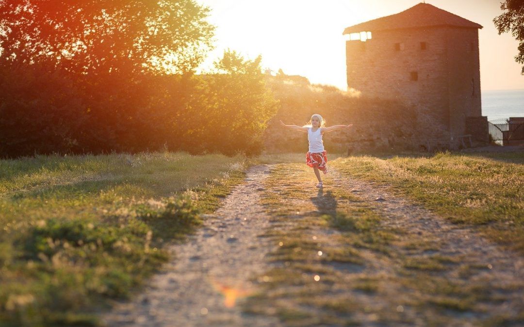 Kleines Mädchen hüpft im Sonnenuntergang auf einem Weg auf der Wiese