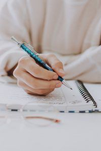 Hand mit Stift und ein Notzibuch