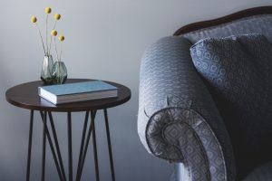 Kleiner Tisch mit Buch und Blume neben einem Sofa als Sinnbild für gemütliche Weihnachtszeit