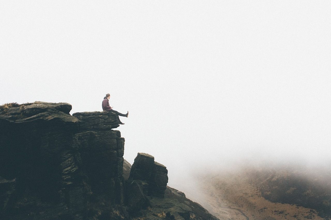 Mann sitzt auf einem Felsen als Sinnbild für ein starkes Selbstvertrauen