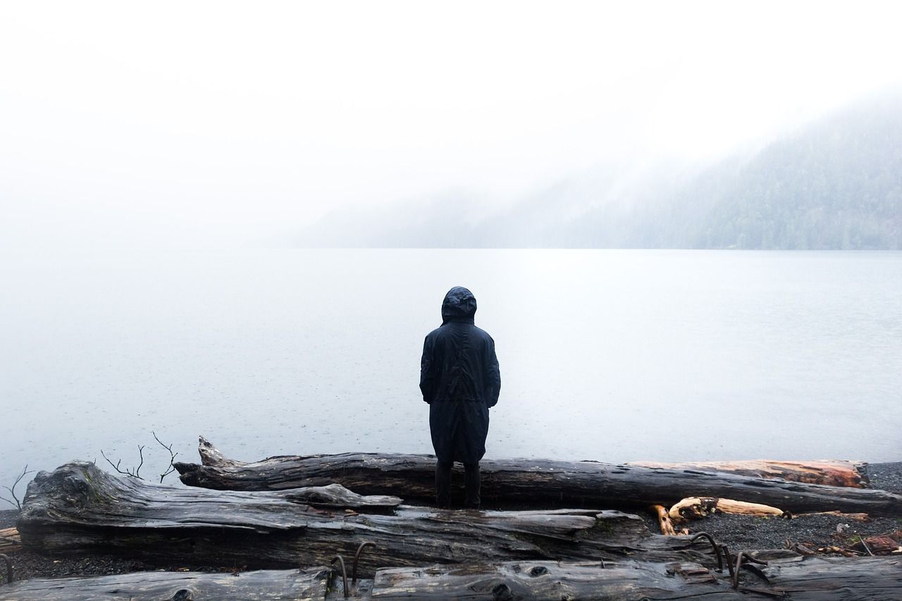 Mensch im Nebel an einem See schaut in die Weite und spürt Kraft in sich - die Resilienz