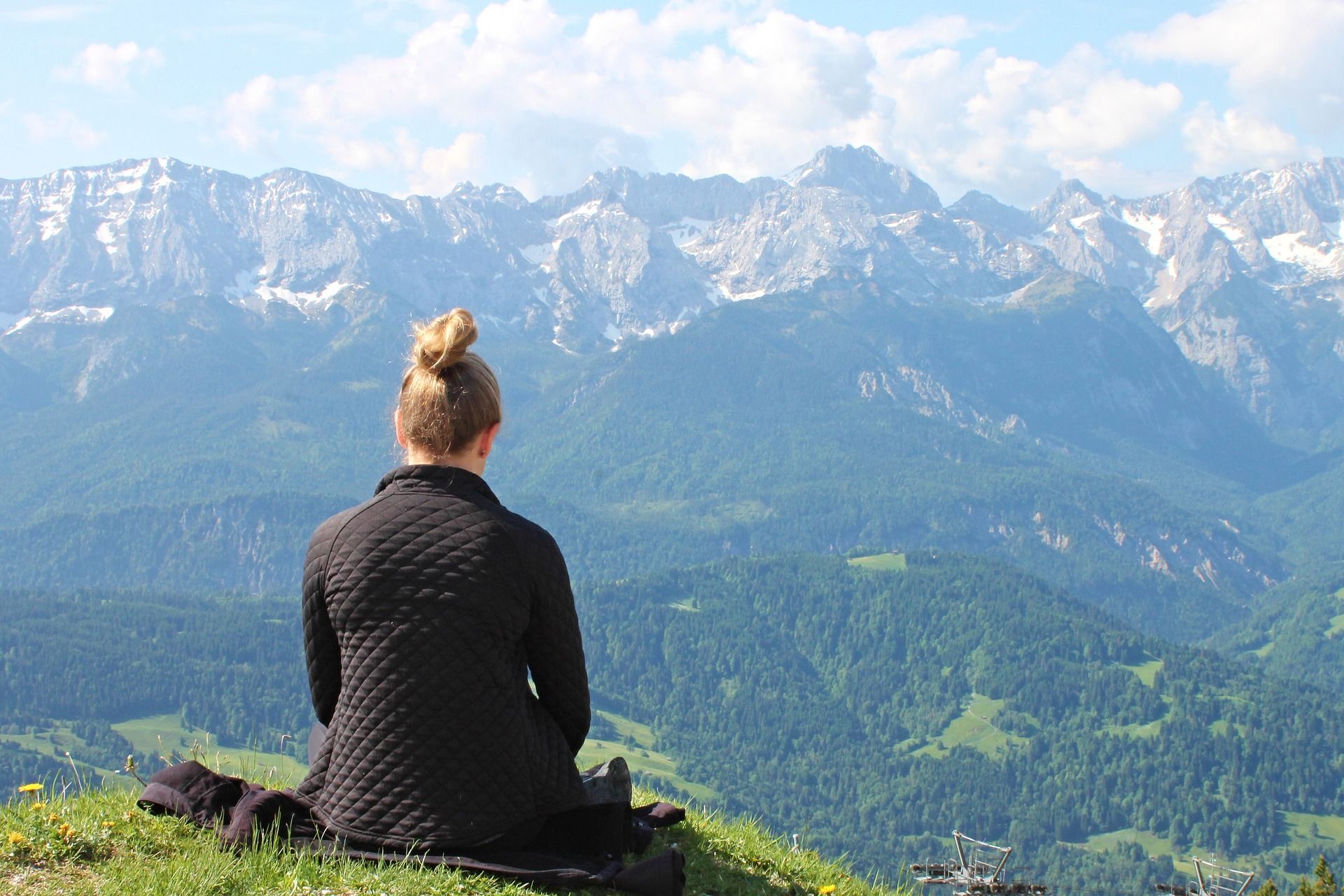 Frau sitzt allein auf einem Berg als Sinnbild dafür, wie man mit Zeiten des Alleinseins die eigenen Stärken sichtbar machen kann