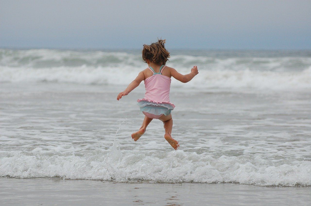 Kind hüpft am Strand in die Luft