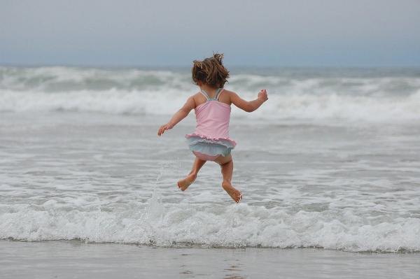 Kind hüpft am Strand in die Luft