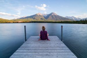 Frau auf einem Steg am Wasser mit Blick auf die Berge als Sinnbild für die Wirkung des Vagusnerv bei Stress