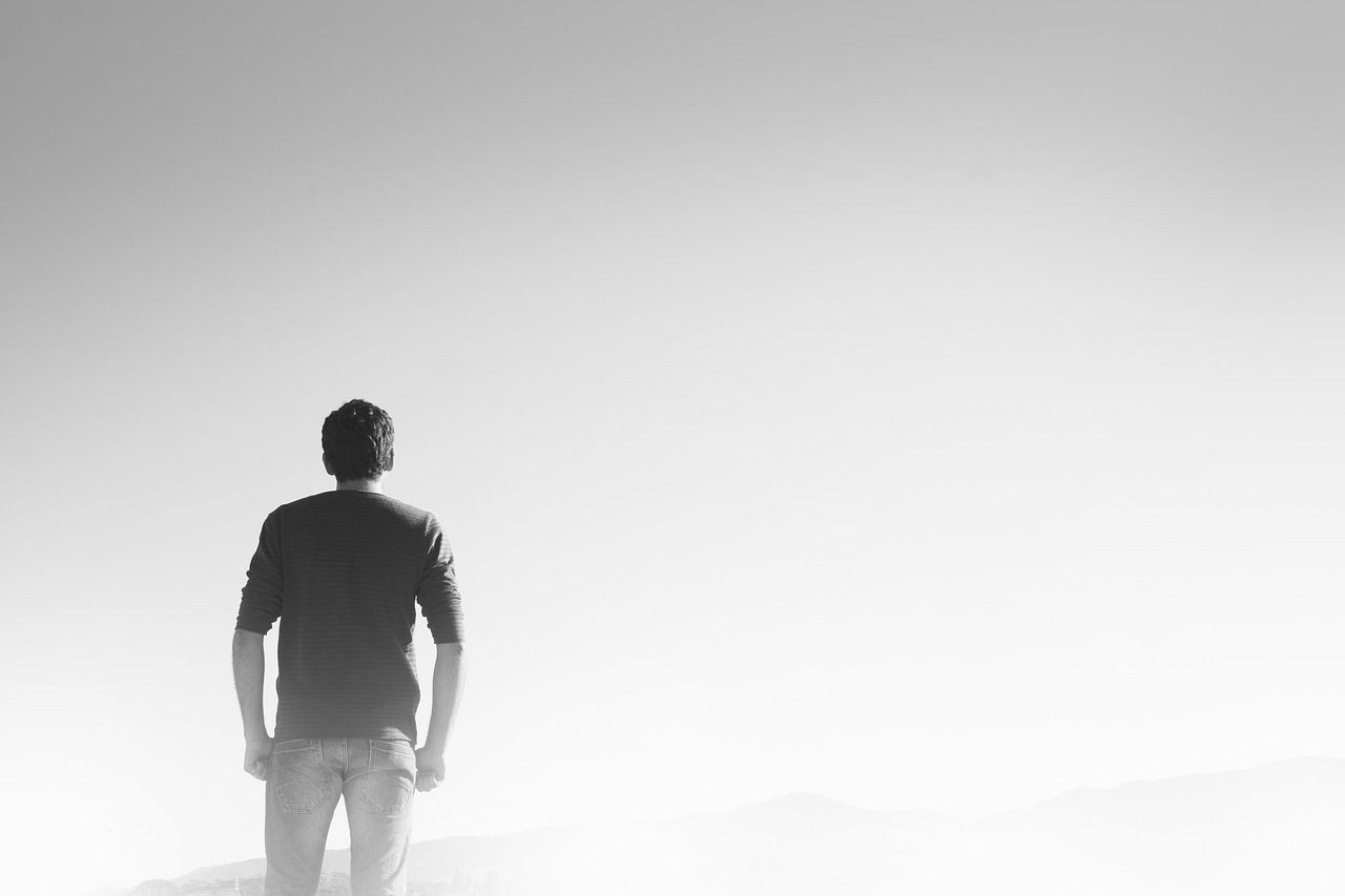Ein Mann von hinten zu sehen. Alles um ihn herum ist grau. Sinnbild für Einsamkeit.