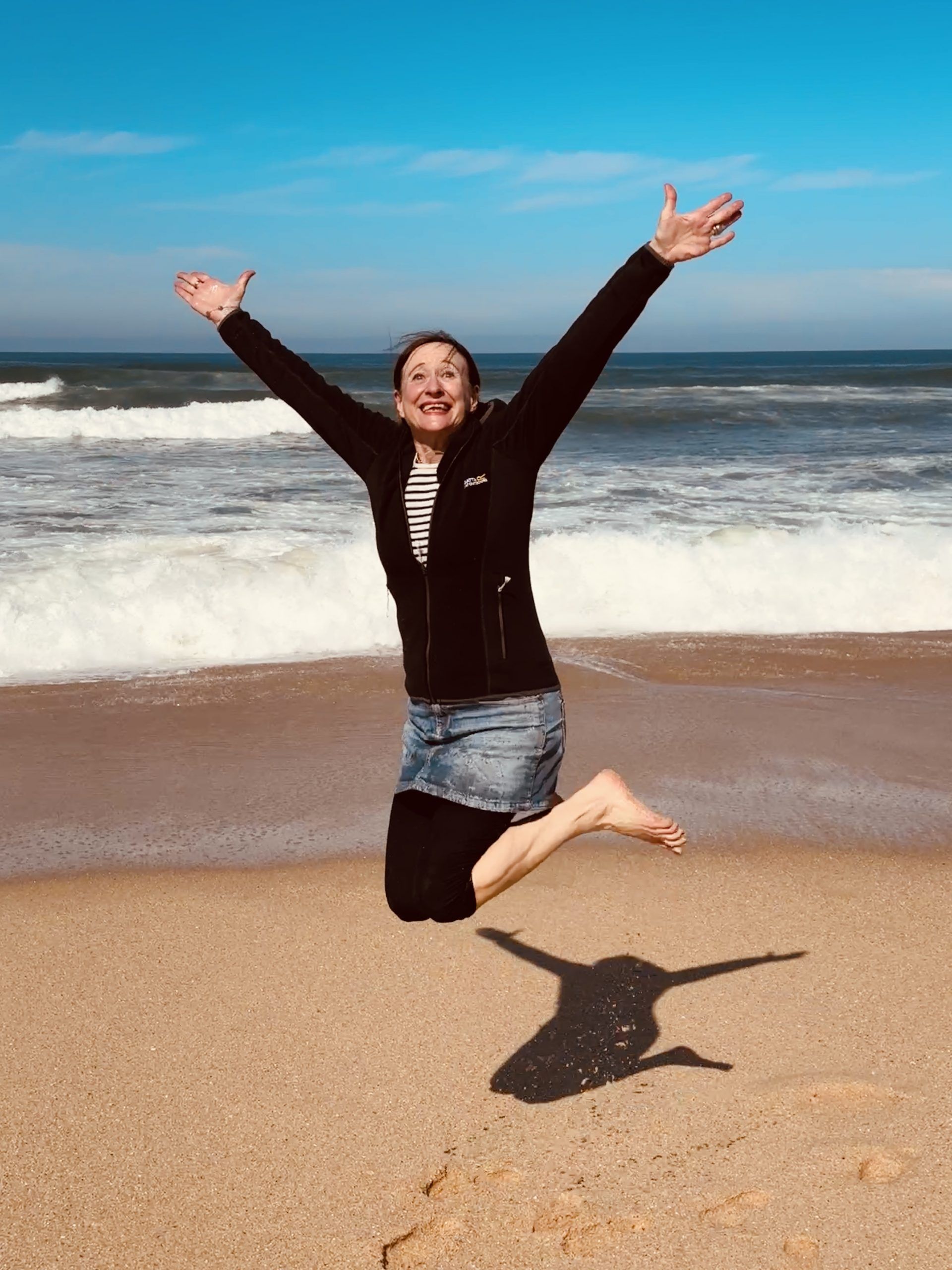 Alexandra Cordes-Guth springt am Strand in die Luft als Sinnbild von Freude