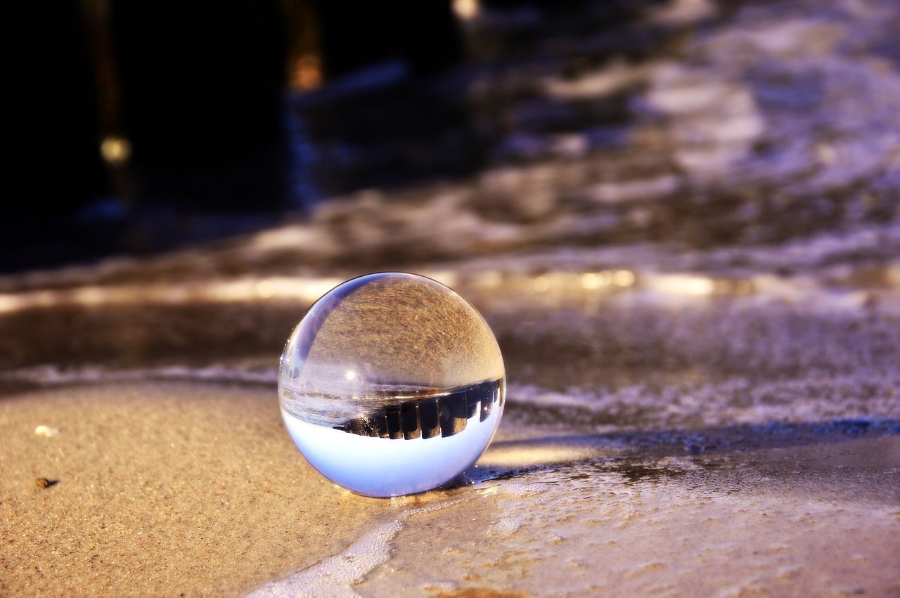 Glaskugel im feuchten Sand als Sinnbild für unsere Vision