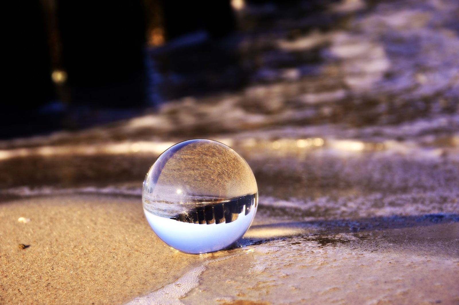Glaskugel im feuchten Sand als Sinnbild für unsere Vision