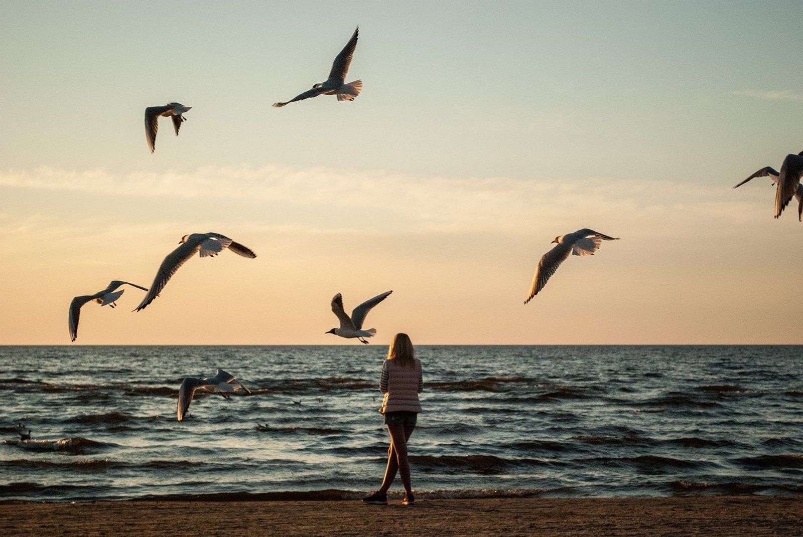 Frau am Meer mit Möwen über sich als Sinnbild für das Lösen von Gedanken und inneren Blockaden
