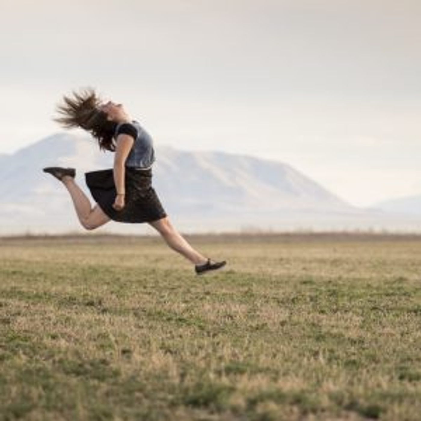 Frau auf einem Feld macht einen Luftsprung