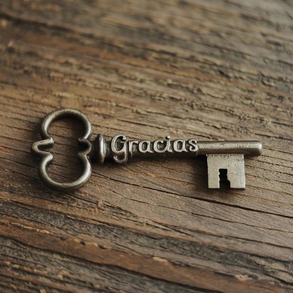 Schlüssel liegt auf Holz mit der Gravur Gracias als Sinnbild für Dankbarkeit gegen negative Gedanken