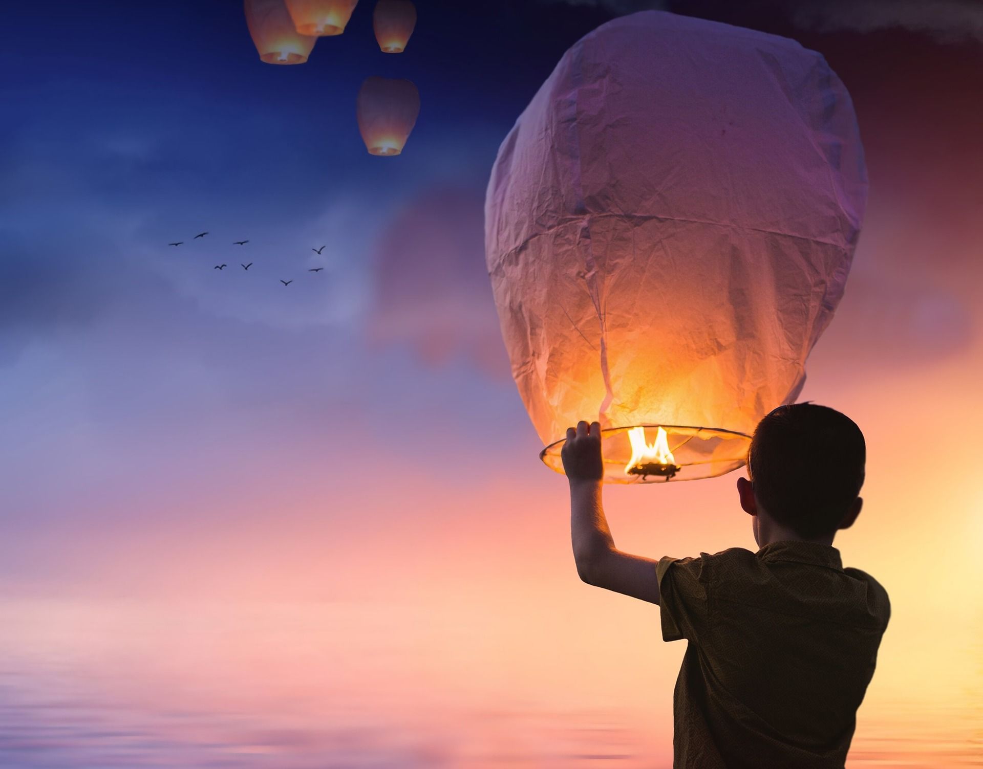 Junge der ein Licht in den Himmel aufsteigen lässt als Sinnbild für das Loslassen