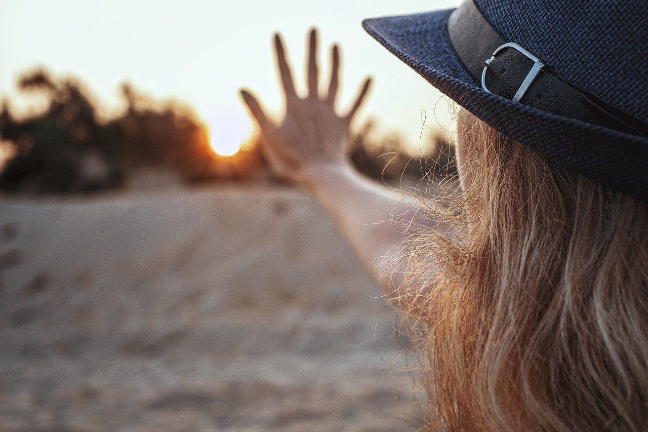 Frau mit Hut schaut in die Sonne