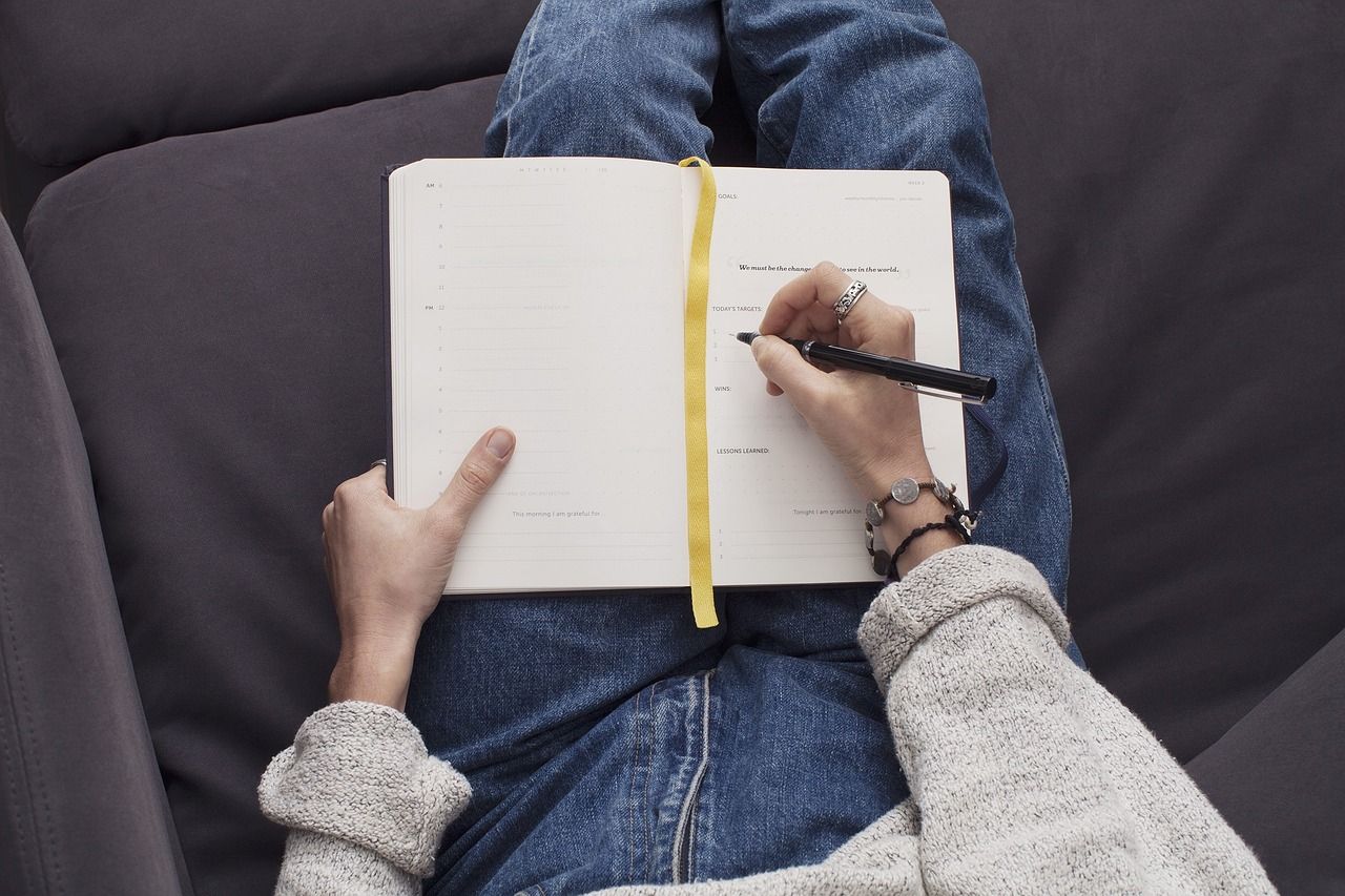 Eine Frau hat ein Schreibheft auf dem Schoß und schreibt mit einem Stift. Und erlebt das kreative und intuitive Schreiben bei Alexandra Cordes-Guth
