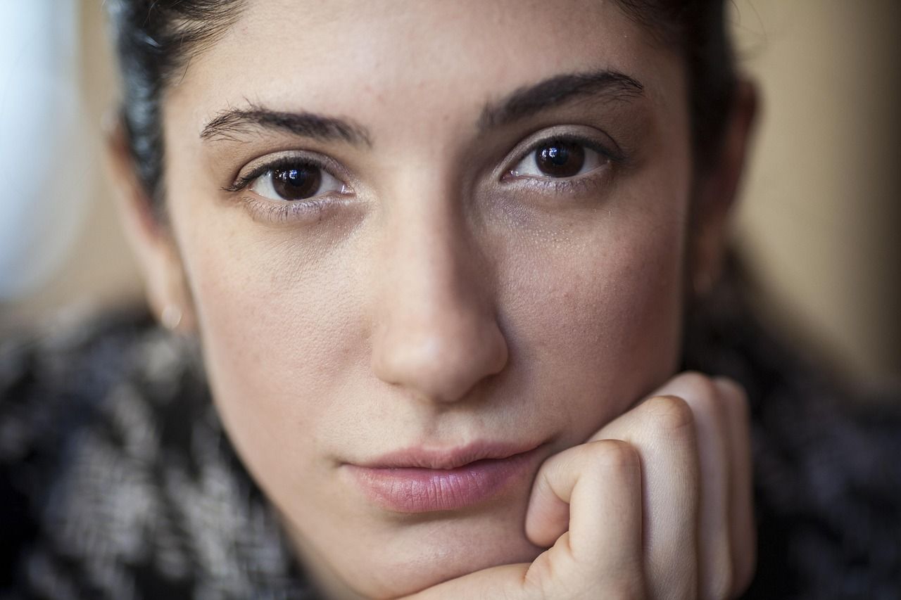 Junge Frau schaut nachdenklich in die Kamera als Sinnbild für die Suche nach positiven Gedanken und Affirmationen