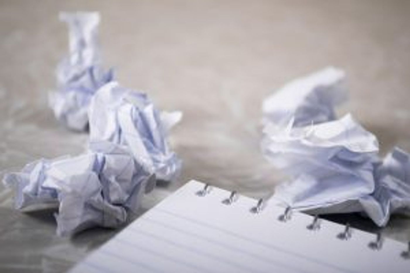 Zerknülltes Papier neben einem Block als Sinnbild für Job-Frust und Bore Out