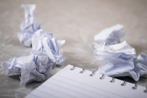 Zerknülltes Papier neben einem Block als Sinnbild für Job-Frust und Bore Out