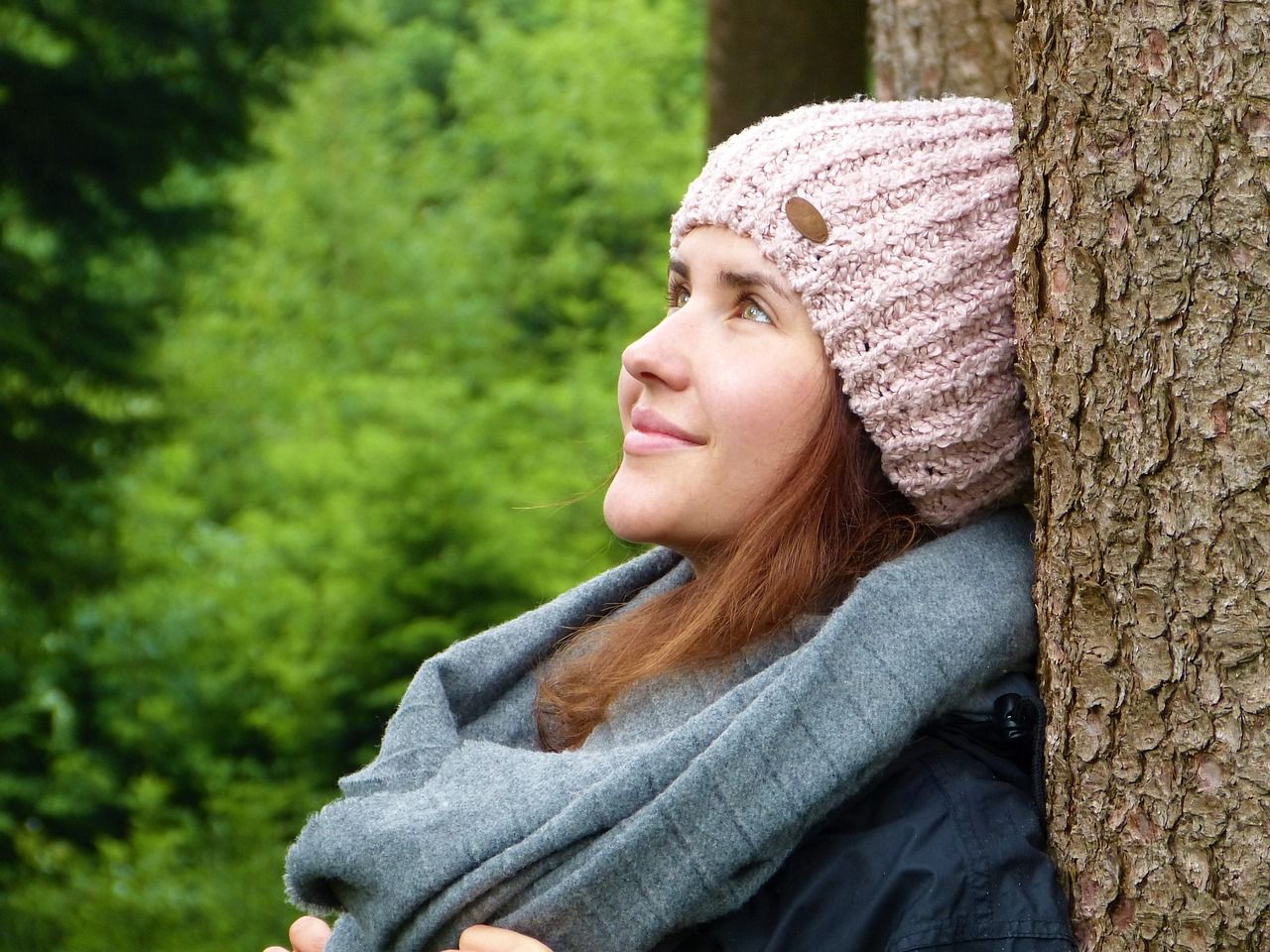 Junge Frau an einem Baum als Sinnbild für inneren Frieden