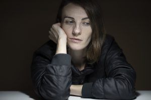 Frau stützt ihren Kopf auf und schaut zur Seite als Sinnbild für Job-Frust