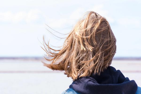 Frau im Wind blickt mutig auf Meer als Sinnbild für den Mut zur Veränderung