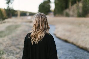 Blonde Frau von hinten zu sehen schaut auf einen Weg als Sinnbild für Wege aus dem Job-Frust
