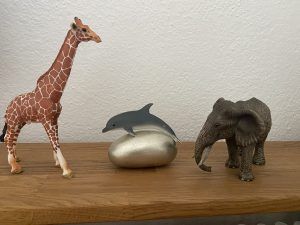 Drei Schleich Tiere: Giraffe, Delfin und Elefant als Symbole für die Glückskindstrategie