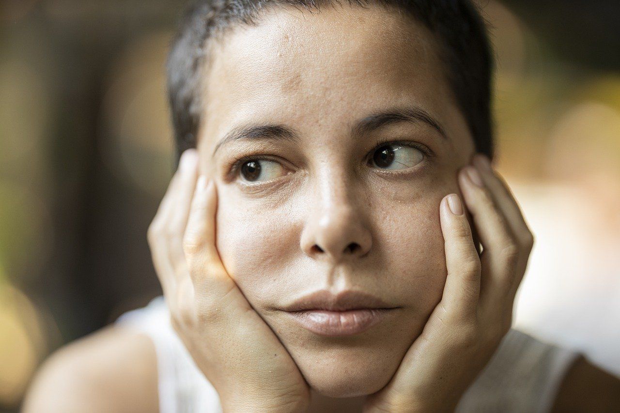 Junge Frau hält ihr Gesicht in die Händen gestützt und schaut sorgenvoll als Sinnbild für die Angst, dass die eigenen Träume doch nichts werden.
